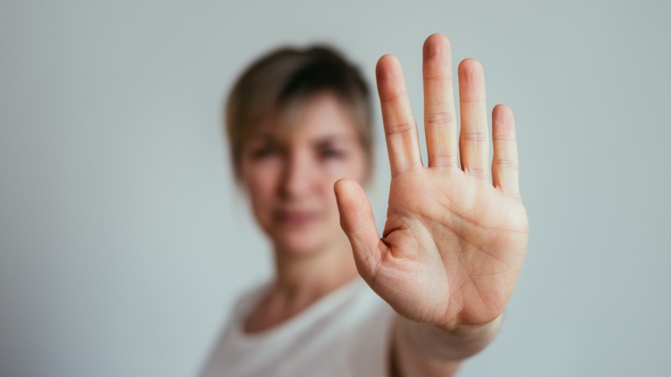 Eine Frau hält ihre Hand nach vorne um damit das "Stop"-Zeichen zu machen