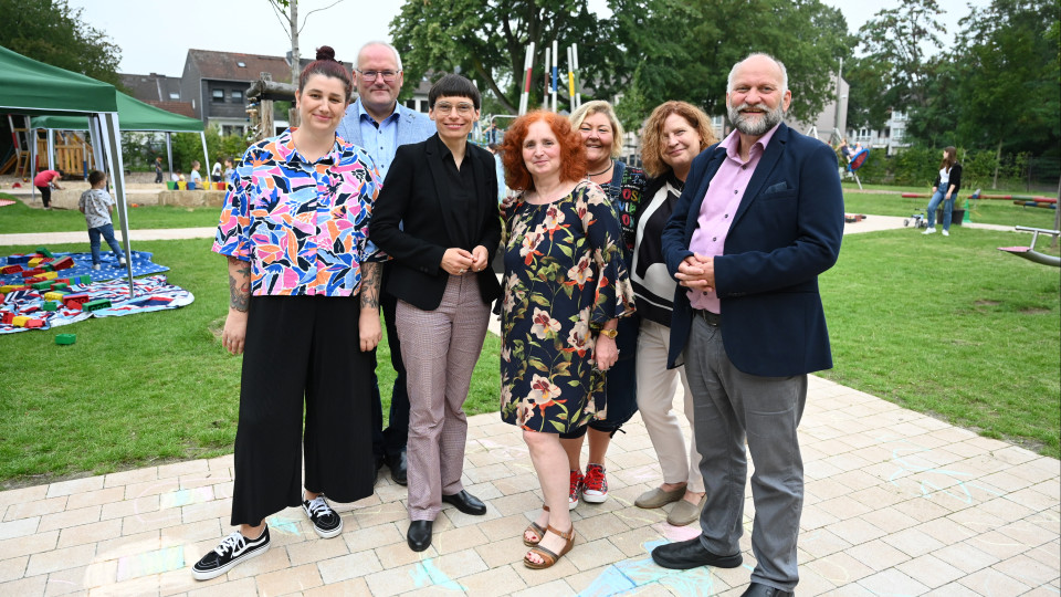 Ministerin Josefine Paul steht mit den Mitarbeitenden der städtischen KiTa Benediktstraße 46 in Duisburg und Verantwortlichen der Stadt Duisburg zusammen für ein Foto.