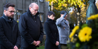 Ministerin Josefine Paul als Vertreterin der Landesregierung, Thomas Kutschaty, Staatsminister a.D., MdL, Vorsitzender des Landesverbandes NRW im Volksbund Deutsche Kriegsgräberfürsorge e.V, Rainer Schmeltzer, Landtagsvizepräsident und ein Mensch von der Bundeswehr nehmen an der gemeinsamen Gedenkveranstaltung zum Volkstrauertag teil. Sie stehen aufgereiht nebeneinander und nehmen an der stillen Kranzniederlegung teil.