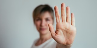 Eine Frau hält ihre Hand nach vorne um damit das "Stop"-Zeichen zu machen