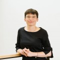 Ministerin Josefine Paul schaut in einer offenen Körperhaltung in die Kamera. Die Hände sind vor dem Oberkörper zusammengefaltet. Der Hintergrund ist eine weiße Wand.