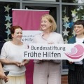 Vor Bannern der Bundesstiftung Frühe Hilfen stehen fünf Frauen, darunter Bundesfamilienministerin Paus und NRW-Familienministerin Josefine Paul, die das Logo der Bundesstiftung Frühe Hilfen in der Hand halten.