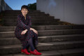 Ministerin Josefine Paul sitzt auf einer Steintreppe, die draußen ist. Frau Paul ist komplett zu sehen. Sie lacht in die Kamera, die Hände liegen auf den Knien.