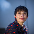 Ministerin Paul schaut nachdenklich lächelnd nach oben links. Der Oberkörper ist nur abgeschnitten zu sehen. 