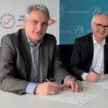 Staatssekretär Lorenz Bahr sitzt mit dem Vorstand der Caritasverband Hamm e. V., Elmar Marx, zusammen an einem Tisch. Beide unterschreiben die Partnerschaftsvereinbarung für die Landesinitiative „Erfolgsfaktor Interkulturelle Öffnung – NRW stärkt Vielfalt!“. Im Hintergrund sind die Pressewämde des Ministeriums. 